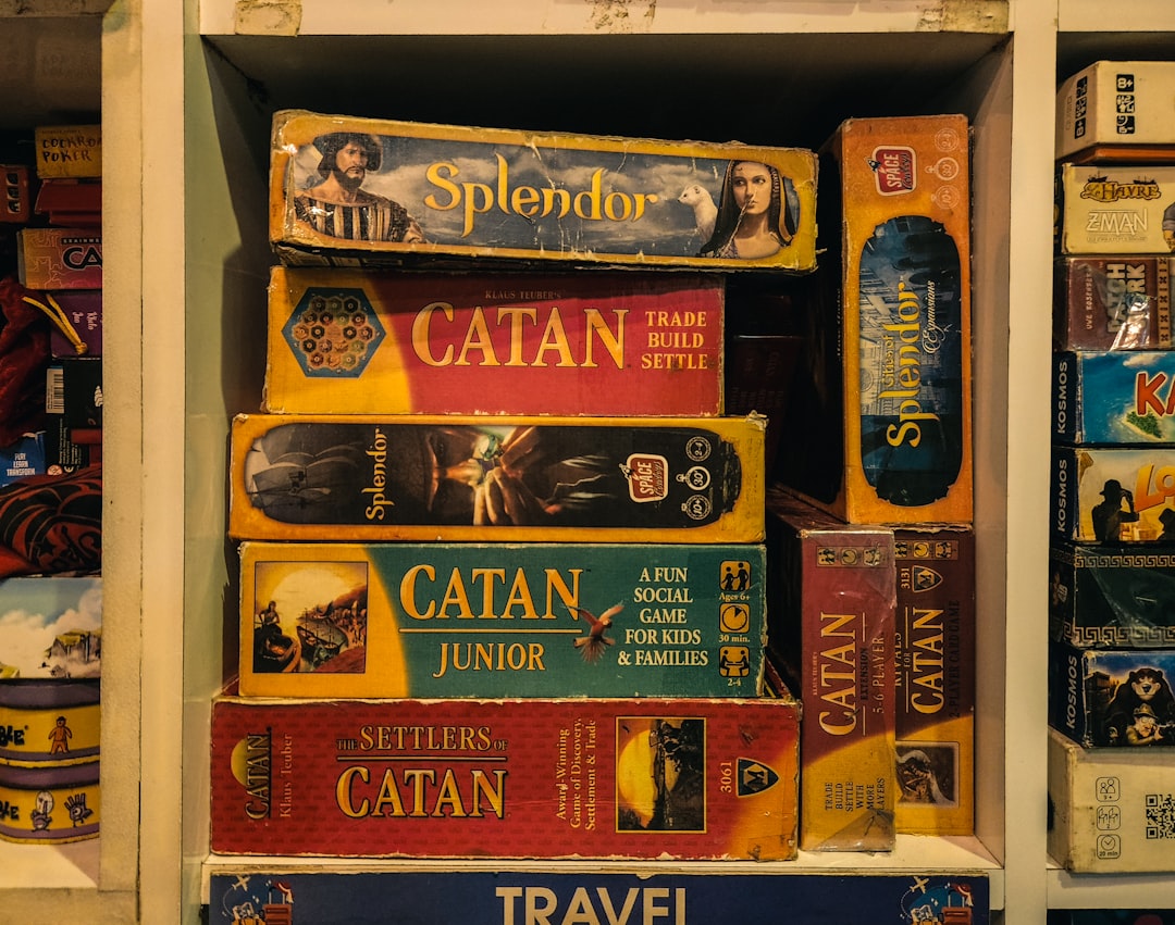 Stack of board games including splendor and catan.