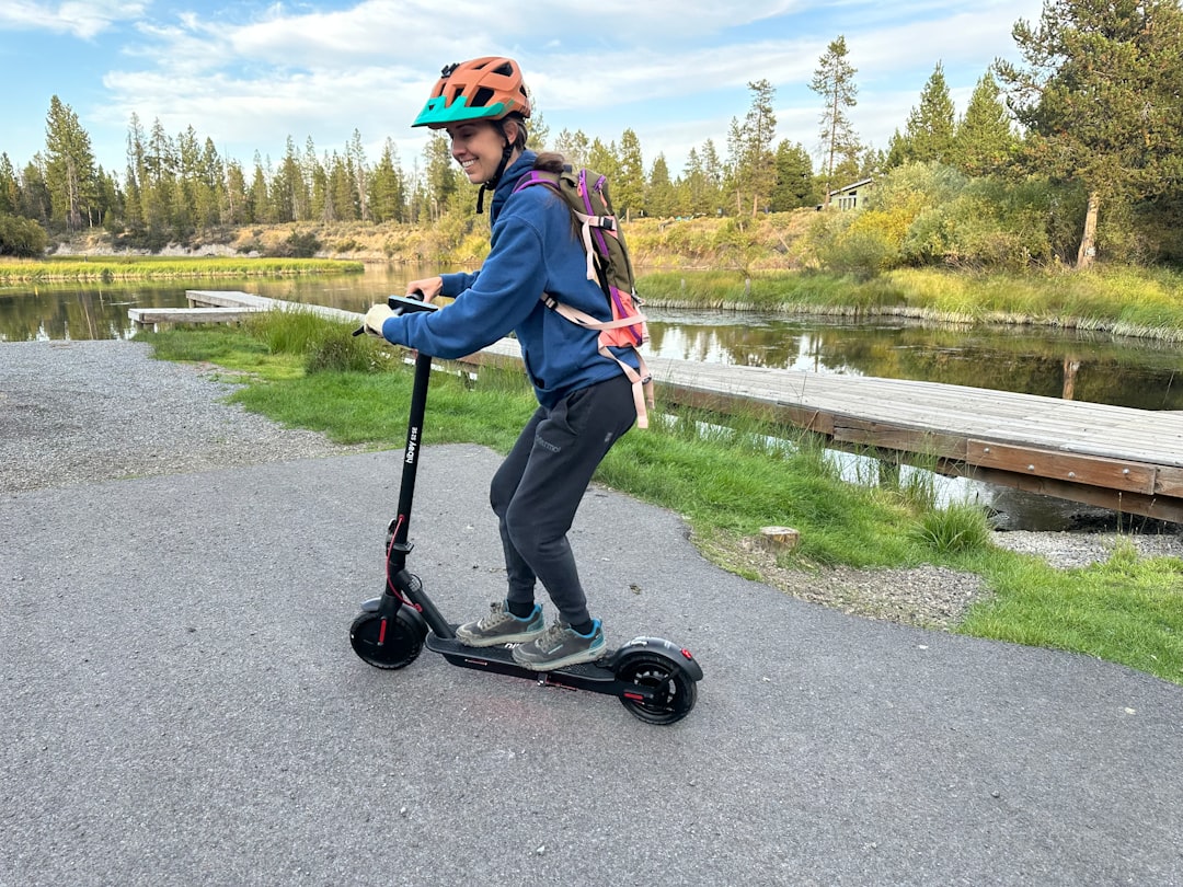 Person riding an electric scooter near a body of water.