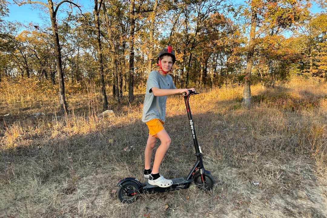 a young boy riding a scooter in a field
