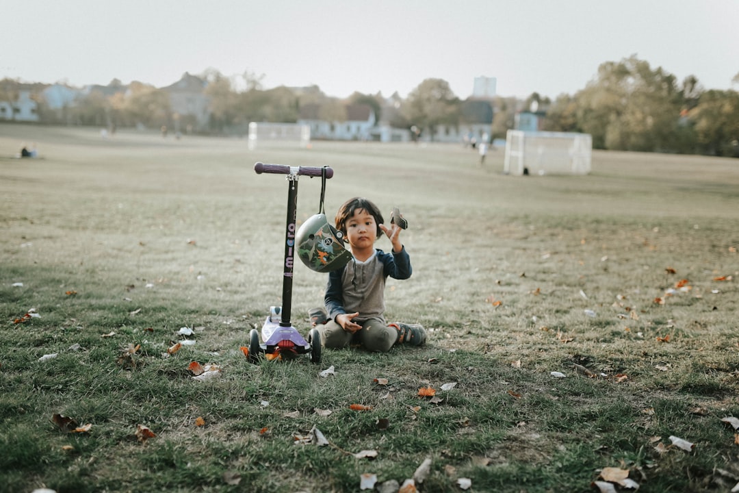 a young boy sitting on the ground next to a scooter