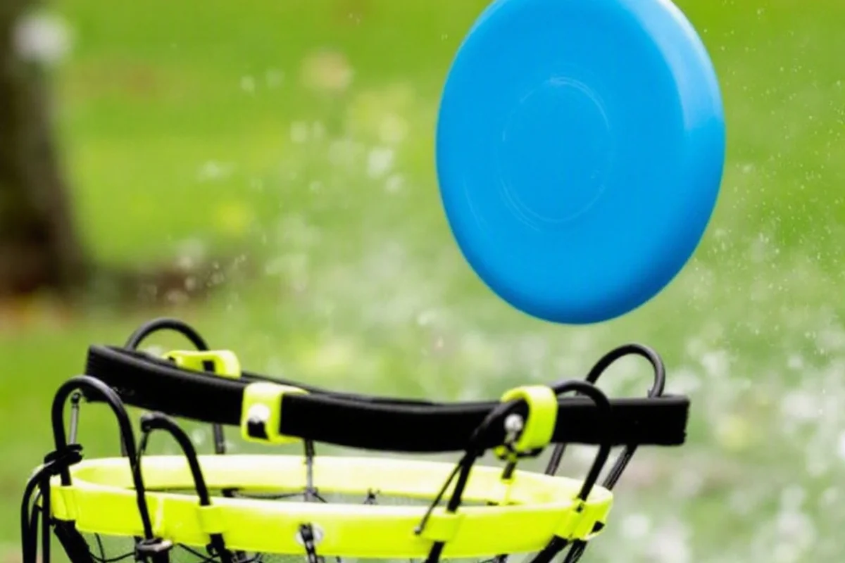 A frisbee about to land in a portable disc golf basket.