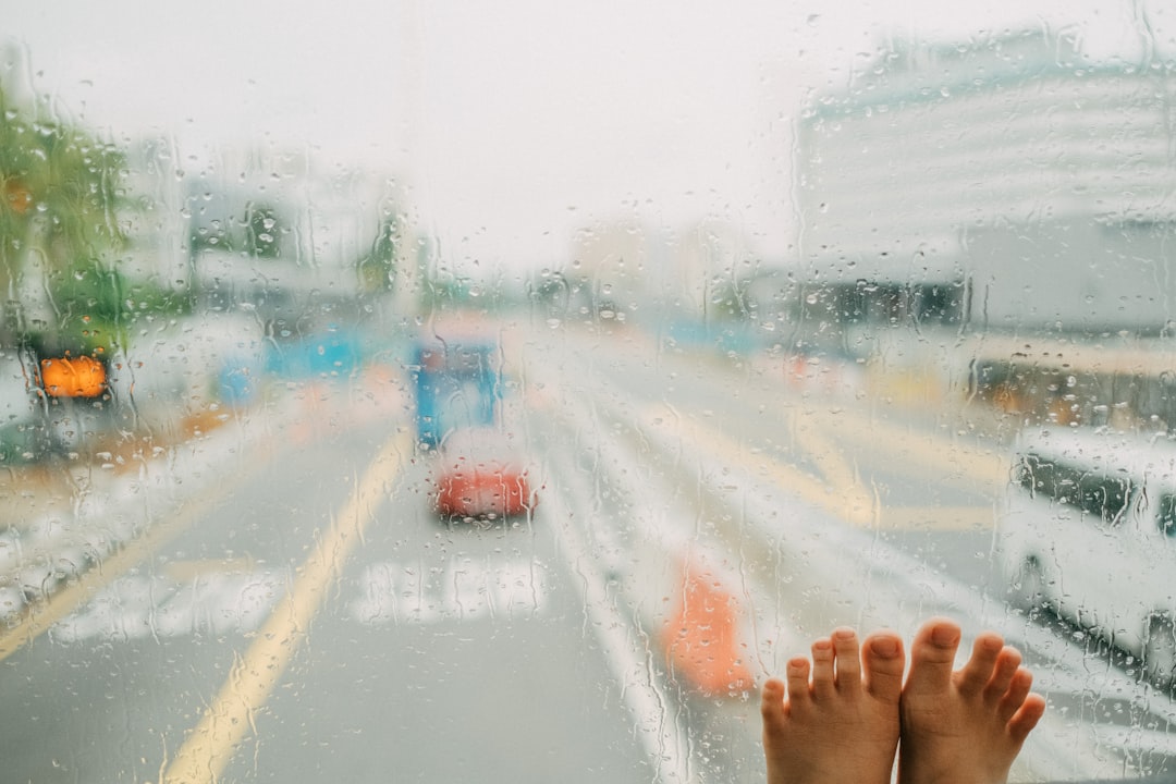 a person's feet sticking out of a window on a rainy day
